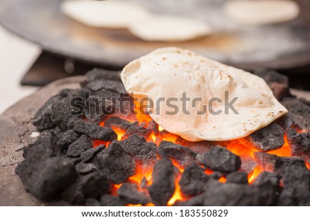 stock-photo-a-roti-indian-flatbread-cooking-on-a-coal-fire-183550829.jpg