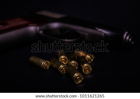 9 mm pistol gun and bullets strewn on black background. Bullets isolated