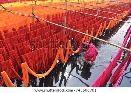 DHAKA, BANGLADESH - OCTOBER 28, 2017: A Bangladeshi worker carries Garments fabric after dries them under the sun at Narayanganj, near Dhaka, Bangladesh on October 28, 2017.