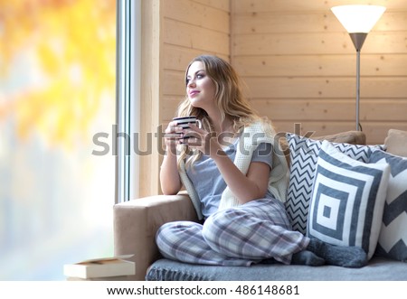 https://thumb7.shutterstock.com/display_pic_with_logo/174604/486148681/stock-photo-young-beautiful-blonde-woman-with-cup-of-coffee-sitting-home-by-the-window-autumn-fall-trees-486148681.jpg