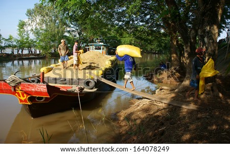 DONG THAP, VIET NAM- NOVEMBER 12: Finish harvest, trader buy rice of farmer, porter carry rice sack up to boat to transport, rice grain filled hold of boat, Dong Thap, Viet Nam, November 12, 2013