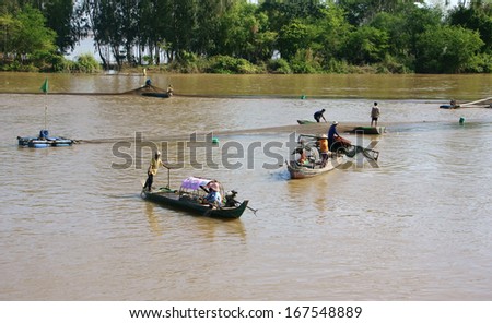 DONG THAP, VIET NAM- NOV 12: Group of fisherman catching fish by net on river, they row the boat along the river and spread a net to catch fish in Dong Thap, Viet Nam on Nov 12, 2013