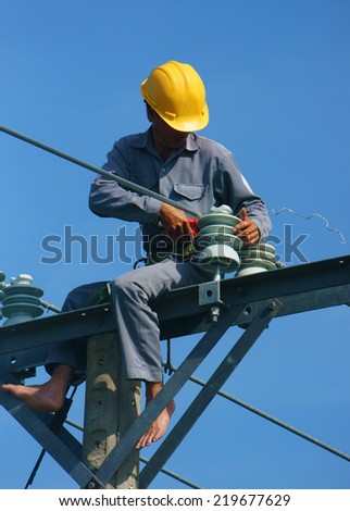 DONG THAP, VIET NAM- SEPT 23: Asian electrician climb high in pole to work, lineman with cable network, man repair electric post danger and unsafe, is industry service, Vietnam, Sept 23, 2014