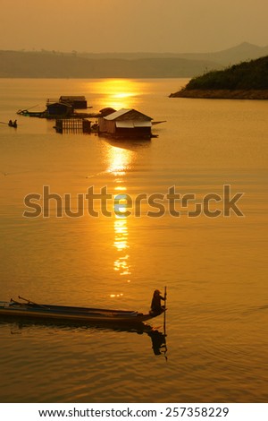Abstract Vietnamese rural at sunset, sun on yellow sky, vibrant color, silhouette of people rowing a row boat on Nam Ka Lake, Dakak, Vietnam, house on water, make amazing landscape of Viet Nam travel