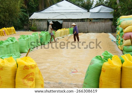 VINH LONG, VIET NAM- MAR 23: Couple of Asia farmer dry rice on drying ground, group of paddy bag to temporary storage when crop finish, Mekong Delta is big Vietnamese granary, Vietnam, Mar 23, 2015