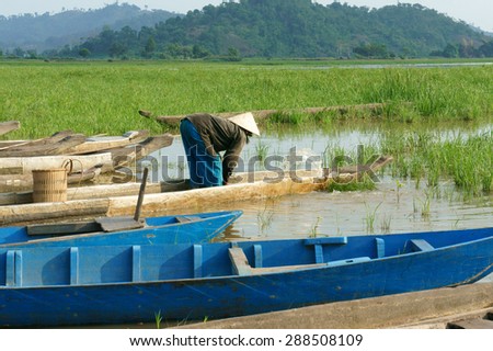 DAK LAK- VIET NAM- JUNE11: Group of Asian farmer go to work by row boat on Lak lake in summertime, family of ethnic minority, grass on lake, amazing view for Asia travel, Daklak, Vietnam, June11, 2015