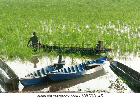 DAK LAK- VIET NAM- JUNE11: Group of Asian farmer go to work by row boat on Lak lake in summertime, family of ethnic minority, grass on lake, amazing view for Asia travel, Daklak, Vietnam, June11, 2015