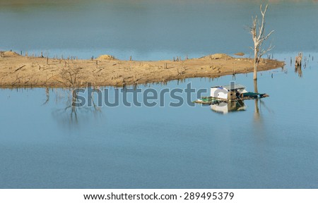Harmony landscape of Asia countryside, lonely floating house on water, beautiful Nam Ka lake at Daklak, Viet nam. Reflection of dry tree, home on river make beautiful scene