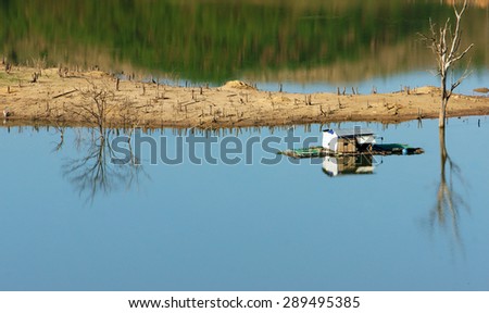 Harmony landscape of Asia countryside, lonely floating house on water, beautiful Nam Ka lake at Daklak, Viet nam. Reflection of dry tree, home on river make beautiful scene