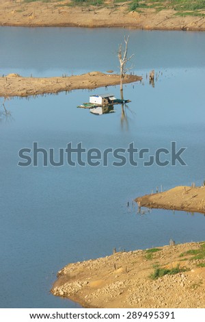 Harmony landscape of Asia countryside, lonely floating house on water, beautiful Nam Ka lake at Daklak, Viet nam. Reflection of dry tree, home on river make beautiful scene