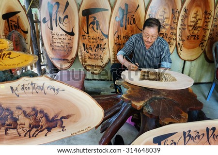 QUY NHON, VIET NAM- AUG 23: Vietnamese artist doing wood engraving by fire pen, man engrave Han Mac Tu poem at souveir shop of Genh Rang tourist area, a famous poet, Quynhon, Vietnam, Aug 23, 2015