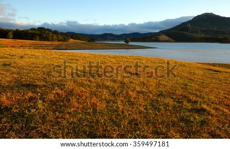 Beautiful panorama landscape at Dalat countryside, Vietnam, amazing wide grass in yellow morning, lake among pine forest, mountain far away, pine tree, wonderful scene for Da Lat, Viet Nam travel