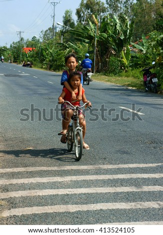 DONG THAP, VIET NAM- SEPT 23, 2014: Two unidentified Asian kid ride bicycle on country road in danger situation, Vietnamese children cycling very dangerous at Mekong Delta, Vietnam