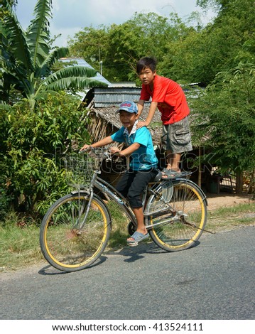 DONG THAP, VIET NAM- SEPT 23, 2014: Two unidentified Asian kid ride bicycle on country road in danger situation, Vietnamese children cycling very dangerous at Mekong Delta, Vietnam