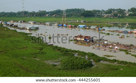 DONG NAI, VIET NAM- JUNE 5: Group of floating house on La Nga fishing village, river with green grass and hyacinth, residence of people who live with fish farming at Dongnai, Vietnam