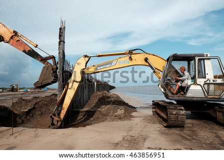 CA MAU, VIET NAM- JULY 16,2016: Vietnamese excavator driver control vehicle to build breakwater at beach to protect seaside from erosion at Camau, Vietnam