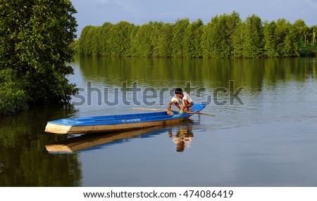 CA MAU, VIET NAM- JULY 16, 2016: Vietnamese man catch fish on river, people and row boat reflect on water, beautiful green tree from mangrove forest make wonderful scene in evening at Mekong Delta