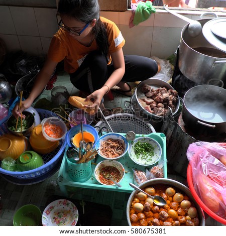 MUI NE, VIET NAM- JAN 22, 2017: Vietnamese woman sell Vietnam food for breskfast, rice spagheti and banh mi in small restaurant, soup with fried fish, bread with braised pork, material show on floor