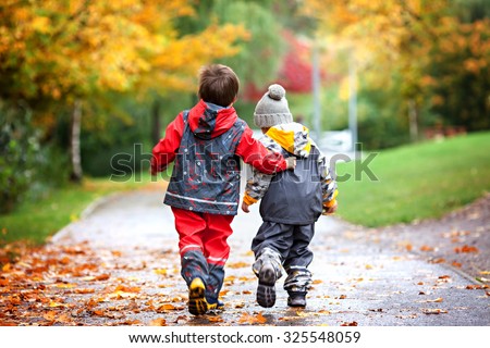 Two children, fighting over toy in the park on a rainy day, autumn time