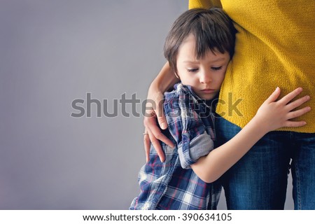 Sad little child, boy, hugging his mother at home, isolated image, copy space. Family concept