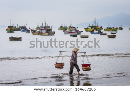 CIRCA APRIL 2010 - QUY NHON, VIETNAM - A woman carries fish baskets by the shore, on 24 April 2010, at Quy Nhon, Vietnam.