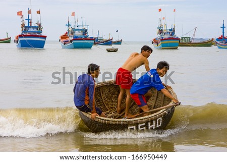 CIRCA JULY 2011 - QUY NHON, VIETNAM - Boys ride a basket boat into the beach, 6 July 2011, in Quy Nhon, Vietnam