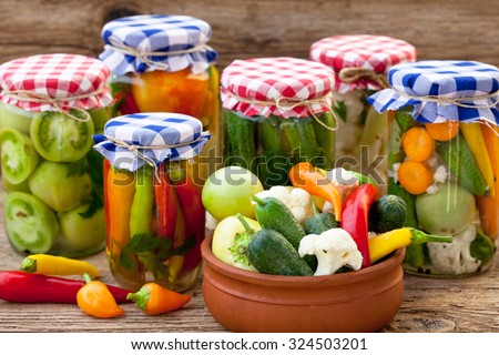 Jars with pickles, green tomatoes, cayenne pepper, mixed salad and chillies