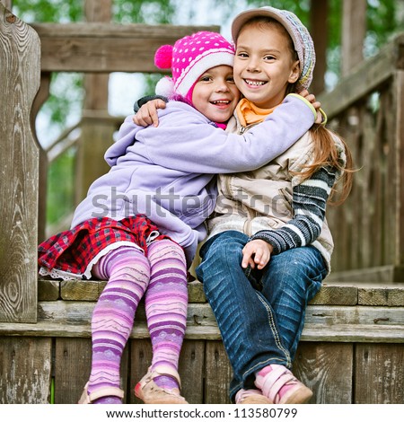 Two happy girls-preschoolers laughs and plays in city children's park.