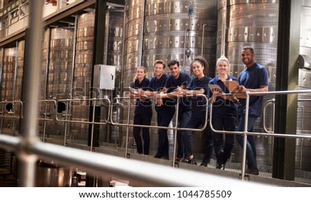 Staff at a wine factory smiling to camera from a gangway