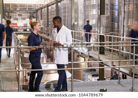 Two staff talking in a modern winemaking factory, close up