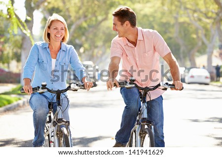 Couple Cycling On Suburban Street