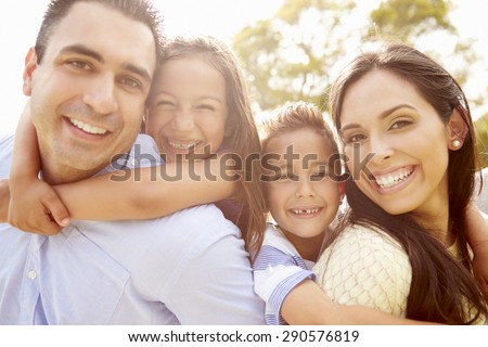 Parents Giving Children Piggyback Ride In Garden