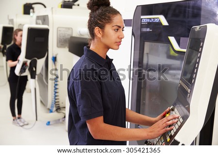 Female Engineer Operating CNC Machinery On Factory Floor