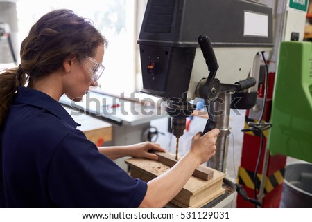 Female Engineer Using Drill In Factory