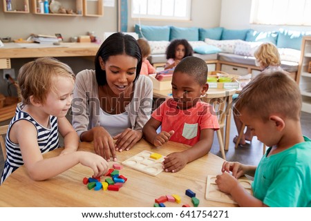 Teacher And Pupils Using Wooden Shapes In Montessori School