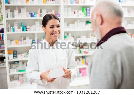 Medicine, pharmaceutics, health care and people concept - Happy female pharmacist giving medications to senior male customer