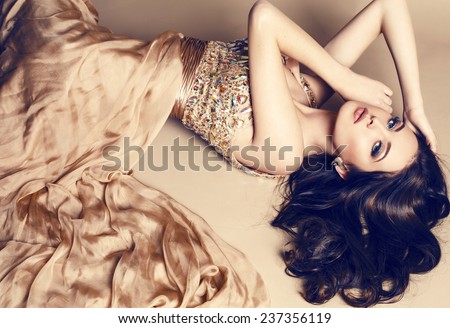 hình ảnh studio thời trang của cô gái trẻ xinh đẹp với mái tóc đen mặc sang trọng váy màu be, nằm trên sàn nhà tại studio