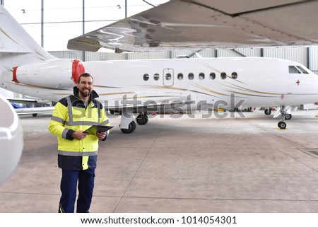 Portrait of an aircraft mechanic in a hangar with jets at the airport - Checking the aircraft for safety and technical function