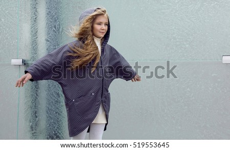 Beautiful young blonde girl in a coat and boots posing for fashion, children's clothing