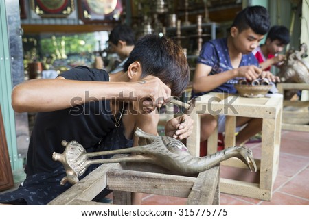 Bac Ninh, Vietnam - Sep 12, 2015: Junior craftsmen making copper handicraft products in traditional way (hand work) in Dai Bai village. Junior people are major labors in traditional works in Vietnam.
