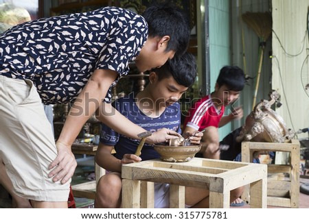 Bac Ninh, Vietnam - Sep 12, 2015: Junior craftsmen making copper handicraft products in traditional way (hand work) in Dai Bai village. Junior people are major labors in traditional works in Vietnam.