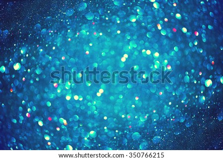 Christmas Blue Background. Glowing Holiday Abstract Defocused Background With Snowflakes and Stars. Blurred Bokeh