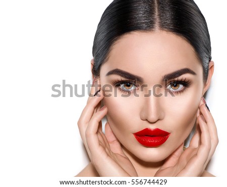 Gorgeous Young Brunette Woman face portrait. Beauty Model Girl with bright eyebrows, perfect make-up, red lips, touching her face. Sexy lady makeup for party. Isolated on white background