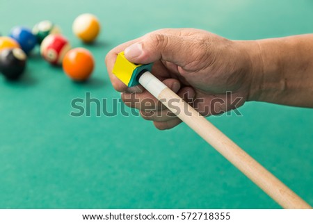 stock-photo-hand-applying-chalk-on-tip-of-billards-pool-stick-with-table-and-ball-at-background-572718355.jpg