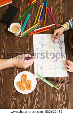 Happy family. Children's and Father hands painted with felt-tip pens. Top view creative photo of hands little boy and Father on vintage brown wooden table.
