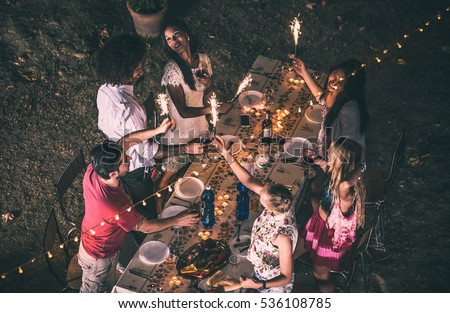 Group of friends making barbecue in the backyard at dinner time