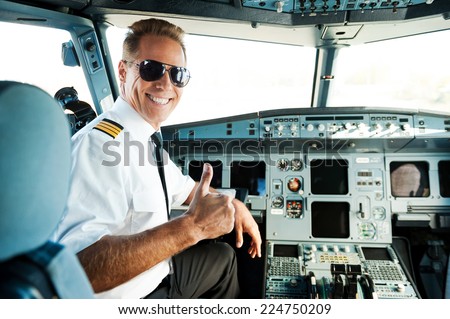 Ready to flight. Rear view of confident male pilot showing his thumb up and smiling while sitting in cockpit