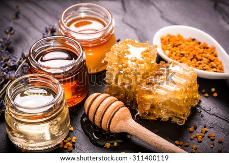 Honey in jar with honey dipper on black stone background