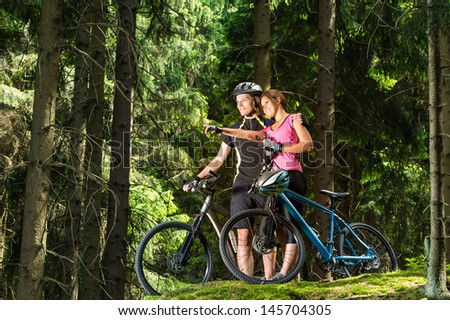 Smiling teen cyclists pointing and standing