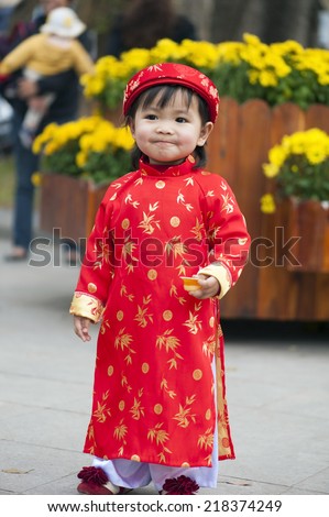 Asia little girl wears Vietnamese traditional long dress ( Ao Dai in Vietnamese) playing on playground by Dinh Tien Hoang street, Hanoi